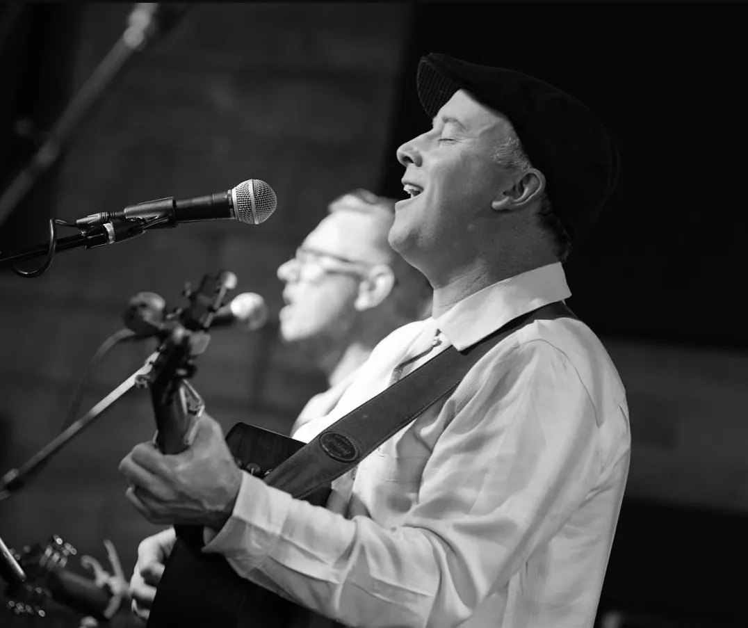 Dave Moran and Mark Sherman singing on stage, in black and white
